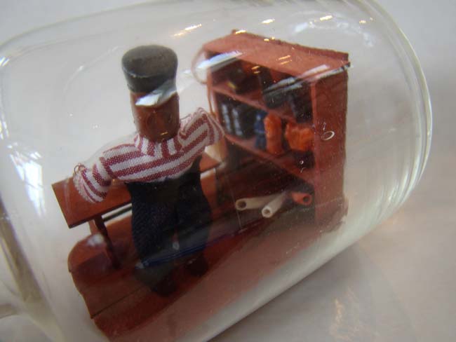A wonderful small ship-in-a bottle depicting a sailor making a ship-in-a bottle — image 3